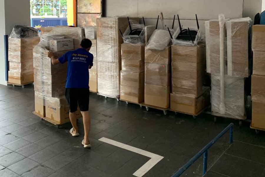 worker pushing trolley of storage moving boxes